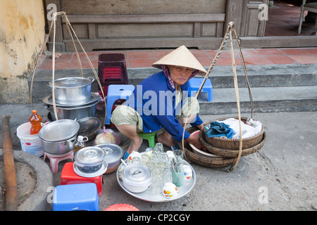 Mujer de venta de alimentos y bebidas en una calle en la ciudad antigua de Hoi An, de la provincia de Quang Nam, Vietnam Foto de stock