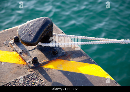 Balizas en el puerto con la soga enroscada alrededor y líneas de color amarillo sobre negro Foto de stock