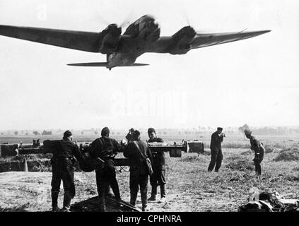 Un avión alemán lanzándose a atacar a Polonia con soldados de una batería flak en primer plano, de septiembre de 1939 b/w Foto de stock