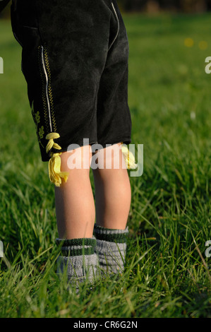 Niño de 5 años de edad vestían pantalones de cuero y vestimenta tradicional socks en el pasto permanente