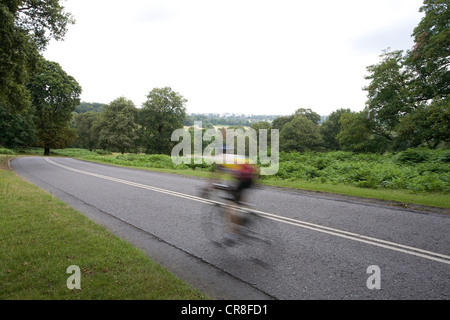 Hombre ciclismo en carretera en Richmond Park, Londres, Reino Unido.