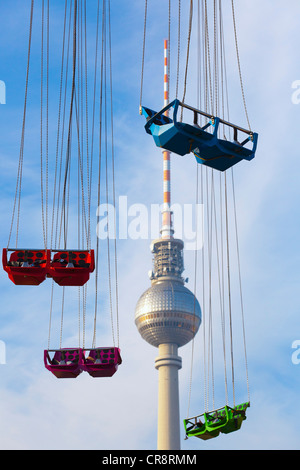 Los asientos vacíos de un swing o Chairoplane carrusel en frente de la torre de televisión en Alexanderplatz, Berlín, Alemania, Europa Foto de stock