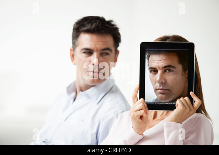Par sentados juntos, mujer sosteniendo el retrato del hombre delante de su rostro Foto de stock