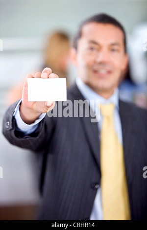 Empresario mostrando su tarjeta de negocios sonriendo en la oficina Foto de stock
