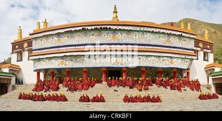 Monjes budistas tibetanos (Sombrero Amarillo o geluk) fuera del Grand Hall del Sutra del monasterio de Labrang antes de ir a la oración. Foto de stock
