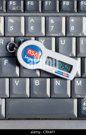 Un token de seguridad RSA SecurID descansando sobre el teclado de un ordenador portátil. Foto de stock