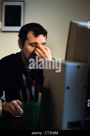 Un hombre está cansado del trabajo de monitor Foto de stock