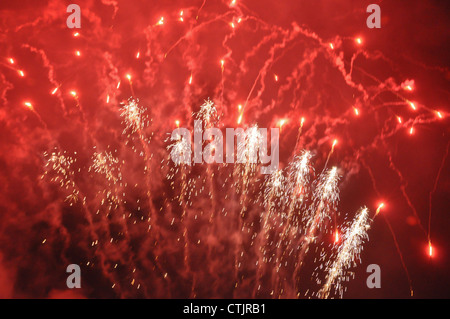 Fuegos artificiales de color rojo brillante y cohetes contra un cielo negro