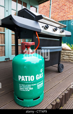 Cilindro verde patio calor bombona de gas propano botella y barbacoa en el patio Foto de stock