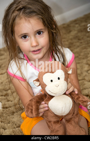 Joven Chica sujetando un mono de juguete Foto de stock