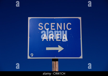 Este cartel que dice zona escénica con la flecha blanca hacia la derecha. signo tiene fondo azul y contra el cielo azul. Foto de stock