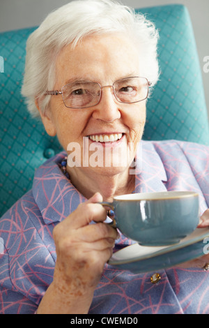 Mujer mayor relax en silla con bebida caliente