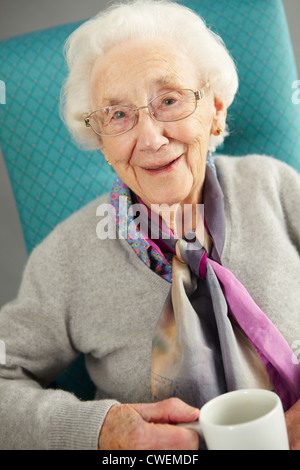 Mujer mayor relax en silla con bebida caliente