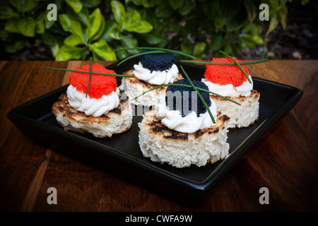 Canapés de caviar rojo y negro decorado con cebollino.