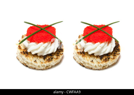 Canapés de caviar rojo y negro decorado con cebollino, sobre fondo blanco.