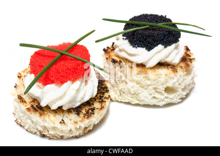 Canapés de caviar rojo y negro decorado con cebollino, sobre fondo blanco.