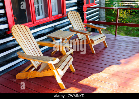 Cabaña de madera cabaña porche con sillas Adirondack Foto de stock