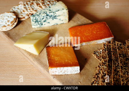 Una selección de quesos ingleses con galletas saladas en una tabla de quesos. Foto de stock