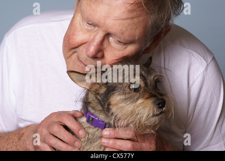 Anciano amorosamente descansa su cabeza en la parte superior de su perro. Foto de stock