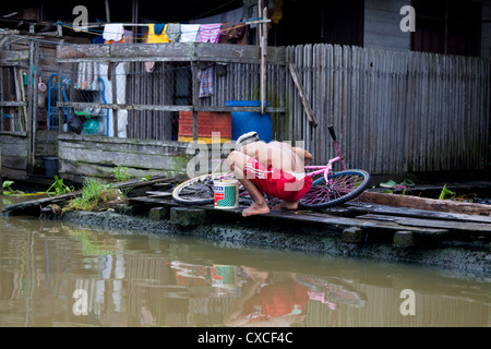 Hombre lavando una bicicleta en el río de Banjarmasin en Indonesia Foto de stock