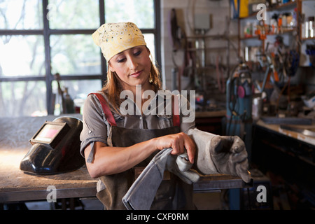 Trabajador de fábrica hispana poner guantes