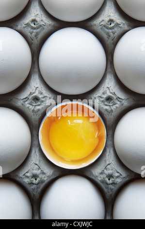 Huevos en caja de cartón con un caparazón roto Foto de stock