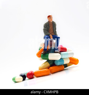 Hombre, figurillas en miniatura, sentado sobre píldoras Foto de stock