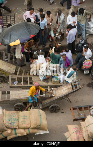 Mirando hacia abajo en cargadores relajante en medio de carretas en Khari Baoli Road, (Spice Market Bazar Chandni Chowk), Vieja Delhi, India
