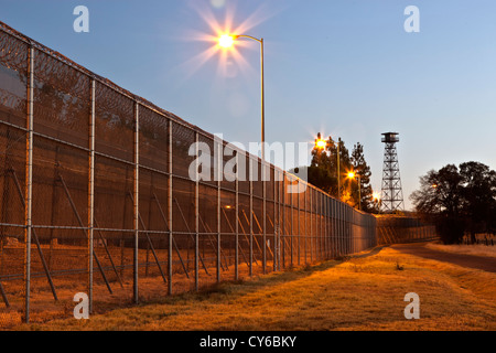 Valla de seguridad penitenciaria, la torre de guardia, antes del amanecer. Foto de stock