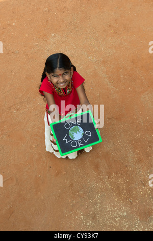 Indian Village chica con un mundo escrito en una pizarra en una aldea india. En Andhra Pradesh, India Foto de stock