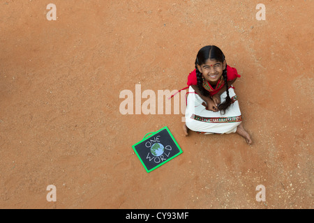Indian Village chica con un mundo escrito en una pizarra en una aldea india. En Andhra Pradesh, India. Copie el espacio. Foto de stock