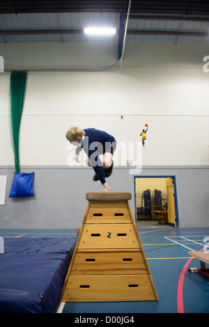 Un muchacho bóvedas en una clase de educación física en el gimnasio de una escuela secundaria completa, Gales, Reino Unido
