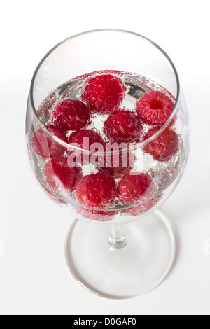 Frambuesas en un vaso de vino con agua con gas Foto de stock