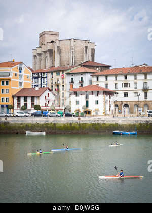 La gente kayak cerca de Zumaia, Guipúzcoa, en el norte de España. El estilo vasco iglesia gótica de San Pedro en el fondo Foto de stock