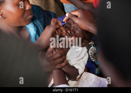 Un niño recibe medicamentos antiparasitarios a un campamento en divulgación de inmunización Kitugutu Village, distrito de Kyenjojo, Uganda. Foto de stock