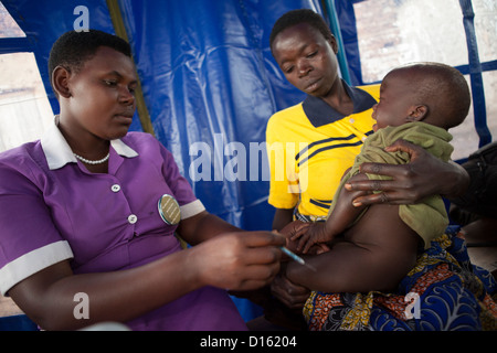 Una mujer recibe una vacuna en una clínica de salud móvil en Kyanjojo, Uganda, África Oriental. Foto de stock