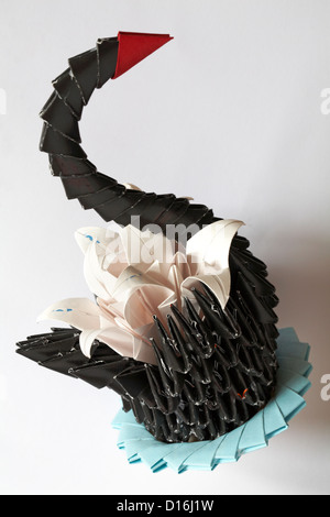 Origami cisne negro con flores aisladas sobre fondo blanco.