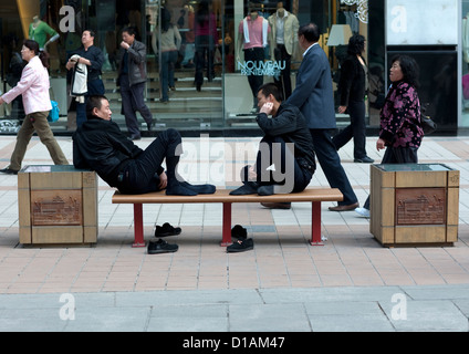 Cansados hombres chinos sentarse en un banco, Beijing, China Foto de stock