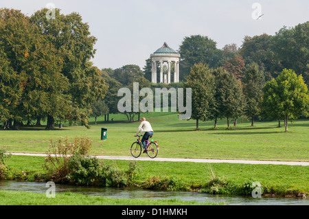Ciclista que aparece junto a Eisbach con Monopterus le en el fondo, el Englischer Garten, Munich, Baviera, Alemania Foto de stock