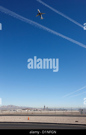 Avión despegar hacia el cielo azul con las estelas de vapor al final de la pista de aterrizaje en el aeropuerto internacional mccarran de Las Vegas Nevada EE.UU Foto de stock