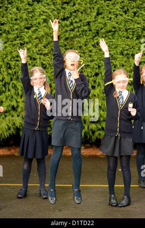 Niñas de la escuela con sus manos durante una lección de ciencias de lanzamiento de cohetes al aire libre en Nuestra Señora y Santa Werburgh Primaria Católica del SC Foto de stock