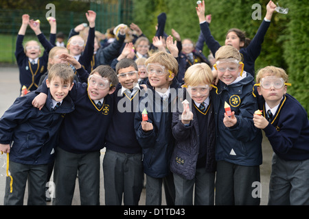 Chicos de escuela con gafas de seguridad durante una lección de ciencias de lanzamiento de cohetes al aire libre en Nuestra Señora y Santa Werburgh Primaria Católica del Sch Foto de stock