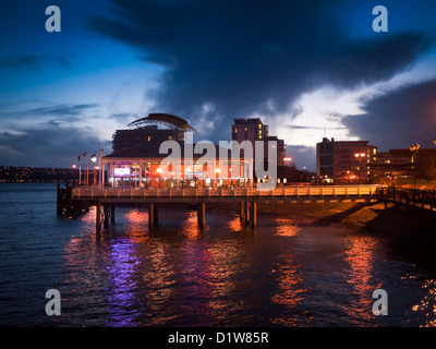 Posiciónese sobre nubes oscuras Mermaid Quay, la Bahía de Cardiff, Gales, en penumbra. Foto de stock
