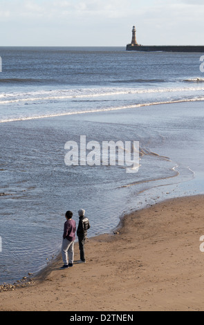 Dos personas en Roker beach con el muelle en el fondo del noreste de Inglaterra Sunderland UK Foto de stock