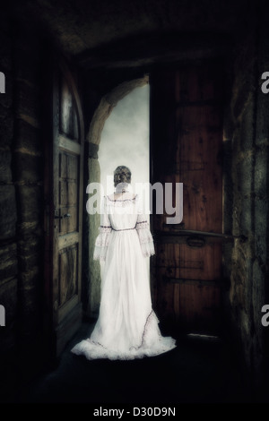 Una mujer en un elegante vestido está de pie en la puerta de un castillo antiguo