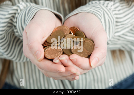 Ahuecada manos sosteniendo un montón de monedas de color bronce.