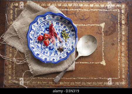 Las semillas de cardamomo, anís y pimientos en un recipiente azul colorido sobre una mesa vintage.