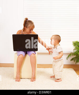 Jovencita con laptop, alejando a su hermanito para dejar sola