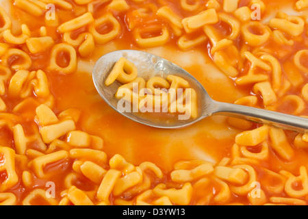En forma de pasta letras de la palabra pasta en una cuchara dentro de cartas en forma de pasta en salsa de tomate Foto de stock