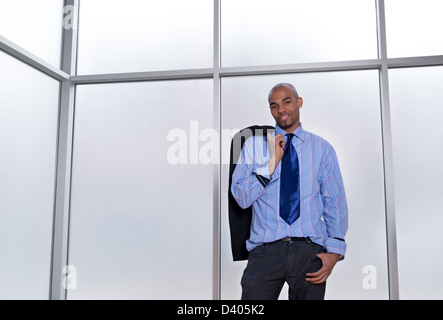 Buen aspecto relajado empresario de pie junto a una gran ventana de la oficina. Foto de stock